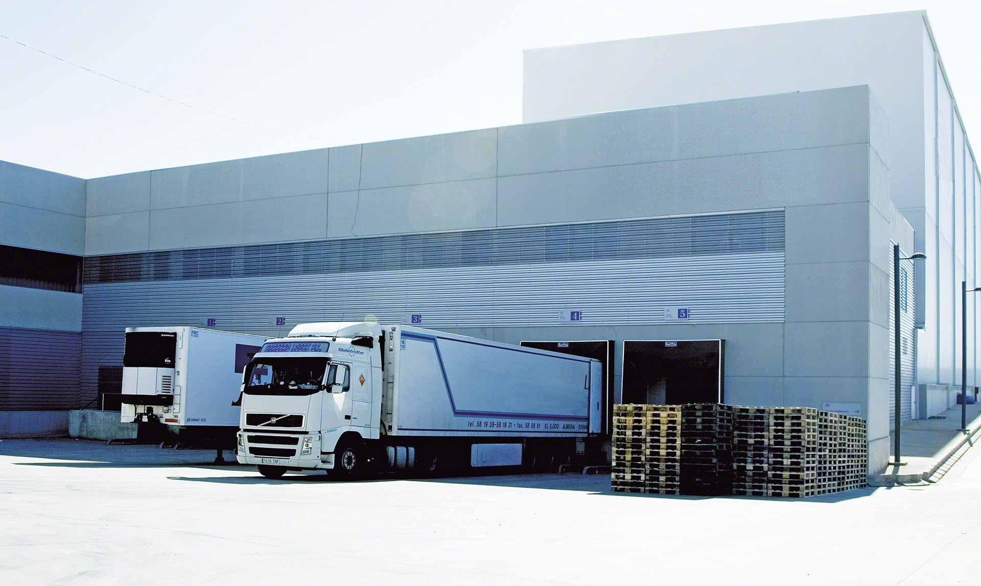 Camiones de mercaderías descargan en la bodega como parte de las operaciones de cross-docking Camiones de mercaderías descargan en la bodega como parte de las operaciones de cross-docking
