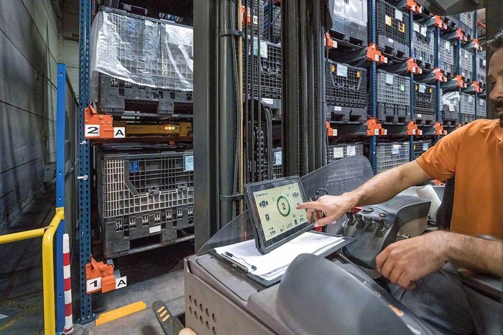 Un operario maneja el Pallet Shuttle desde la grúa con un tablet digital Un operario maneja el Pallet Shuttle desde la grúa con un tablet digital